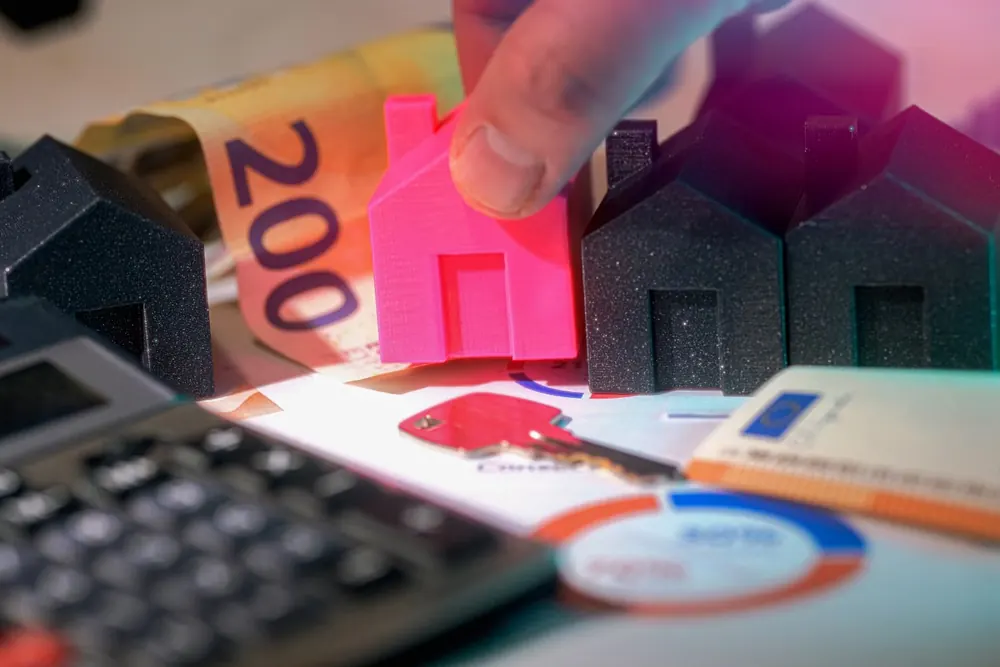 Casas en miniatura, billetes de euro y una calculadora sobre una mesa