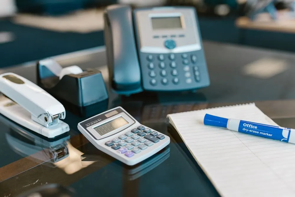 Escritorio con calculadora, teléfono y material de oficina
