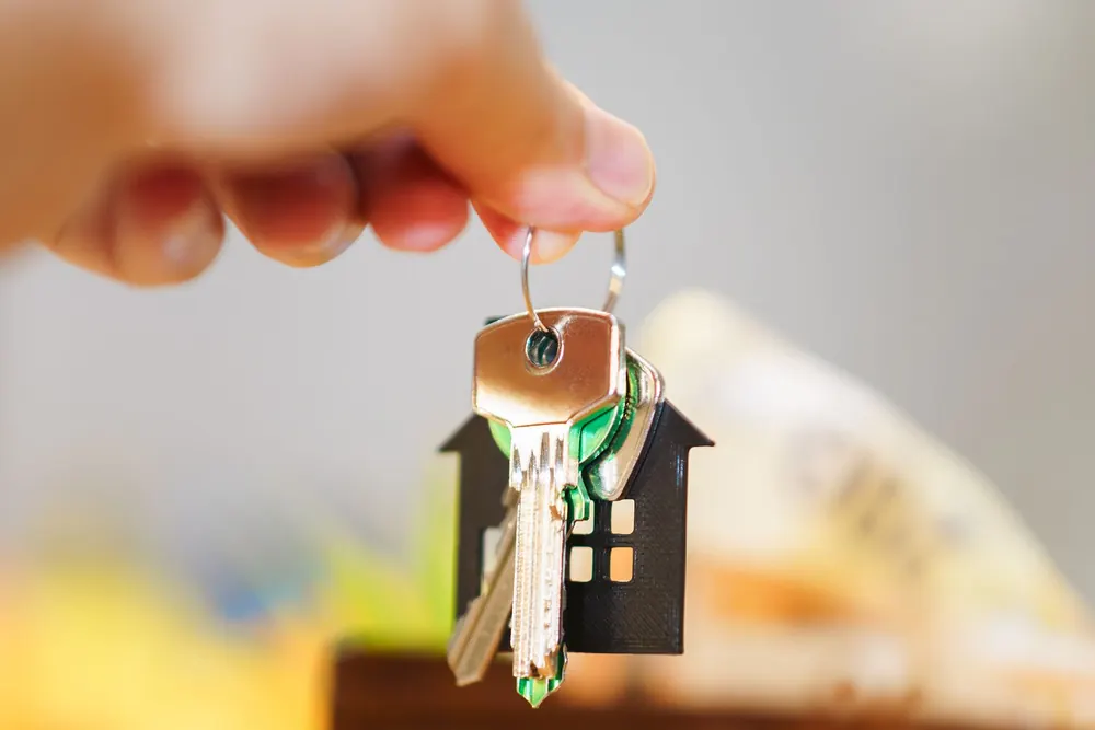 Mano sosteniendo las llaves de una casa con un llavero en forma de vivienda