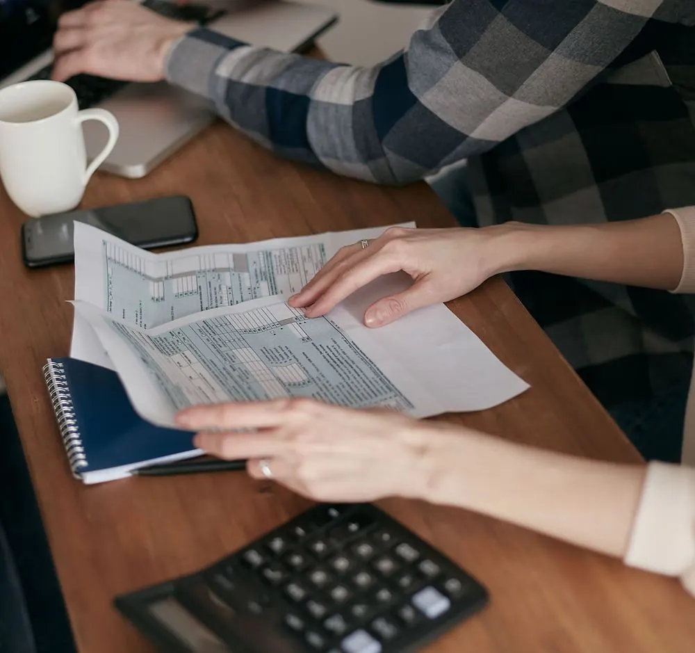 Dos personas revisando documentos con una calculadora