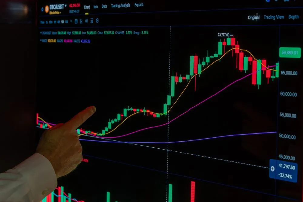 Persona señalando un gráfico de cotizaciones en una pantalla