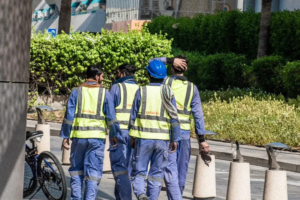 Grupo de trabajadores con chalecos reflectantes caminando por una calle